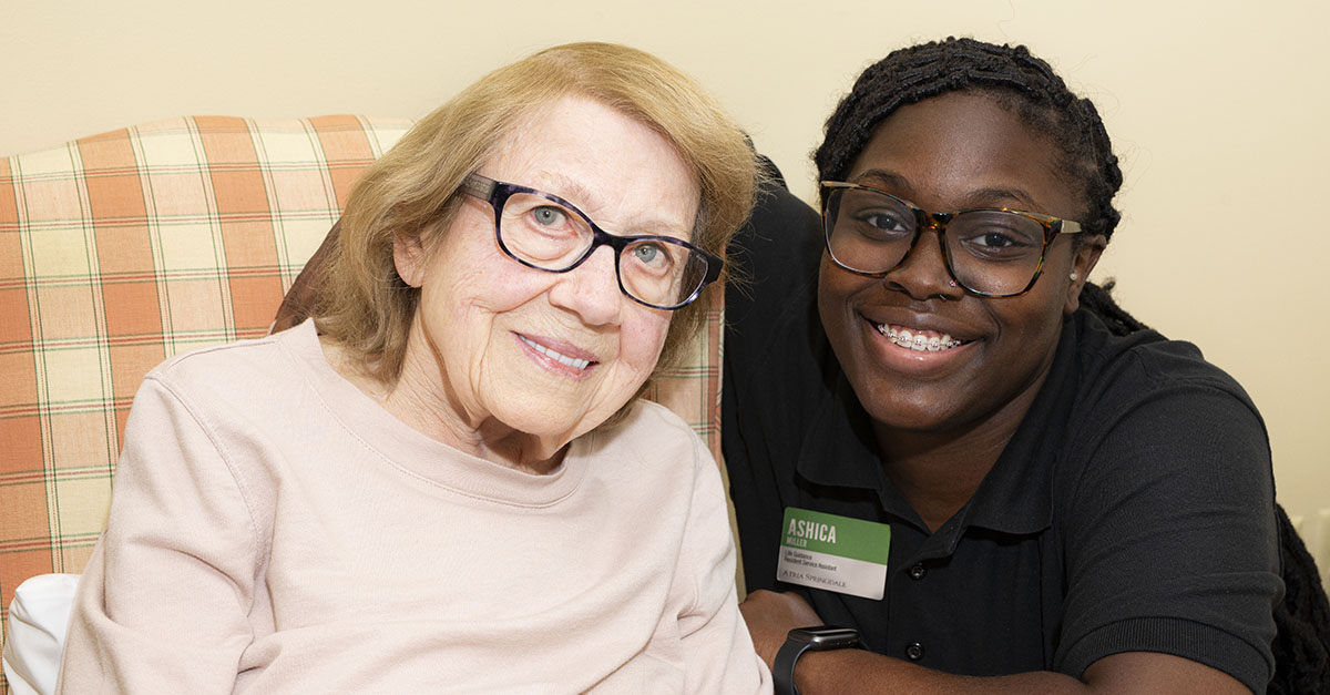 An Atria Senior Living resident and employee smiling for a picture together